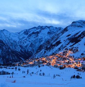 Photo of France ski resort Les Deux Alpes at the evening. You can see a part of resort with many mountains around it.